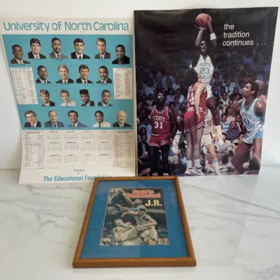 Sale Photo Thumbnail #143: Vintage Michael Jordan and UNC Tar Heels memorabilia, featuring a framed Sports Illustrated magazine cover, a 1986-1987 University of North Carolina basketball calendar poster, and a "the tradition continues..." Michael Jordan dunking poster.