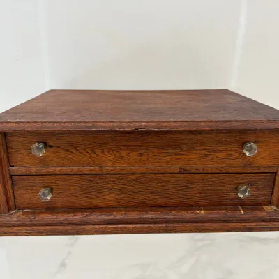 Sale Photo Thumbnail #231: Antique oak tabletop spool cabinet or jewelry chest featuring two drawers with hexagonal glass knobs, showing a rich natural wood grain and classic molded trim.