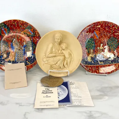 Sale Photo Thumbnail #344: Robert Haviland & C. Parlon Limoges "La Dame à la Licorne" collector plates paired with an A. Santini "The Pensive Madonna" alabaster relief plate, complete with original certificates and booklets.