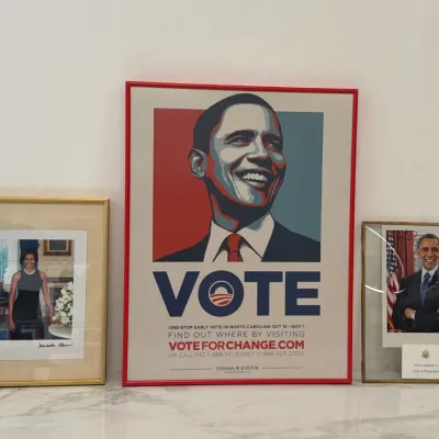 Sale Photo Thumbnail #233: Collection of Barack Obama presidential campaign memorabilia, featuring a framed Shepard Fairey "VOTE" poster from the 2008 election alongside framed portraits of Barack and Michelle Obama.