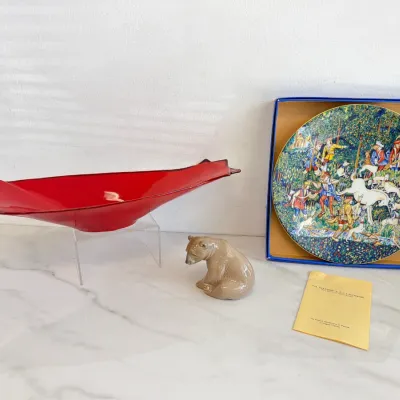 Sale Photo Thumbnail #250: Robert Haviland & C. Parlon Limoges porcelain collector plate "La Chasse à la Licorne" in its original box, displayed alongside a vintage red art glass centerpiece bowl and a small ceramic bear figurine.