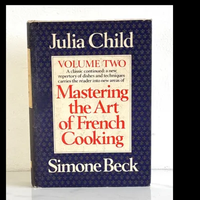 Sale Photo Thumbnail #188: Vintage hardcover copy of "Mastering the Art of French Cooking, Volume Two" by Julia Child and Simone Beck, featuring its original blue patterned dust jacket with some light shelf wear.