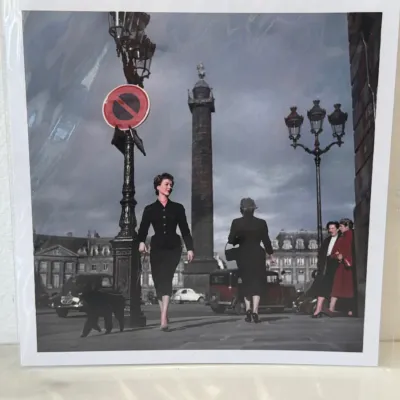 Sale Photo Thumbnail #280: photographic print depicting a 1950s Christian Dior fashion scene at Place Vendôme in Paris, presented in a protective plastic sleeve.