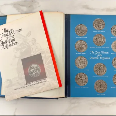 Sale Photo Thumbnail #85: Franklin Mint "The Great Women of the American Revolution" collector's album and accompanying informational booklet, featuring a collection of fine pewter art medals minted for the DAR.