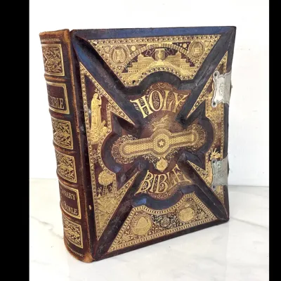 Sale Photo Thumbnail #210: Antique Victorian Holy Bible featuring an ornate, deeply embossed leather cover with elaborate gold gilt detailing and metal clasps.
