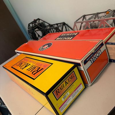 Assorted model train boxes, including a yellow RailKing by M.T.H. Electric Trains box and orange Lionel Electric Trains boxes, displayed...