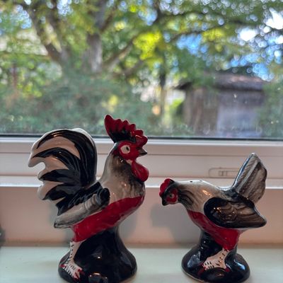 Vintage ceramic rooster and hen salt and pepper shakers, featuring a bold black, white, and red glazed finish.