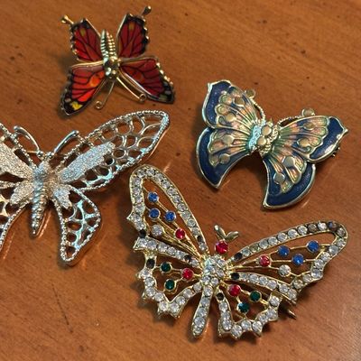 Collection of vintage butterfly brooches, featuring enameled, openwork silver-tone, and rhinestone-embellished designs.