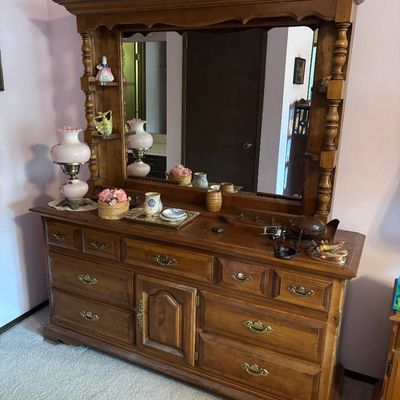 Vintage wooden dresser with a large attached mirror, featuring turned wood supports, built-in display shelves, and brass hardware.
