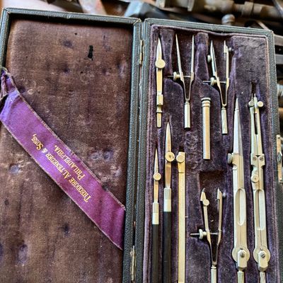Vintage Theodore Alteneder & Sons drafting instrument set in its original purple velvet-lined case, showing some wear consistent with...