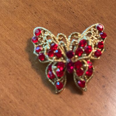 Vintage gold-tone filigree butterfly brooch adorned with vibrant red rhinestones.
