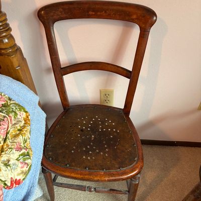 Antique wooden side chair featuring a curved backrest and a perforated plywood seat secured with metal tacks.