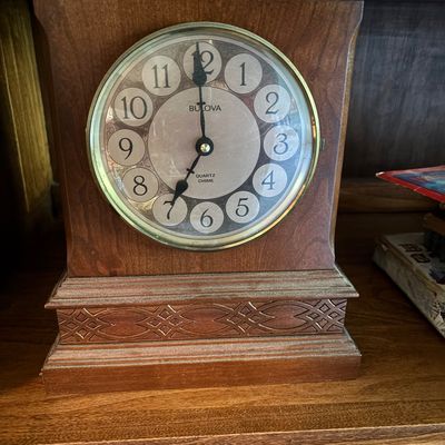 Vintage Bulova quartz chime mantel clock in a wooden case with carved geometric detailing along the base.