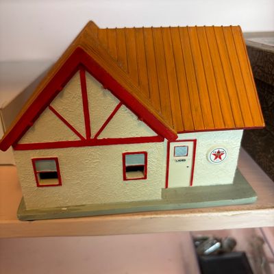 Vintage Texaco toy service station restroom building, featuring a Tudor-style facade with red trim and a Texaco logo emblem.