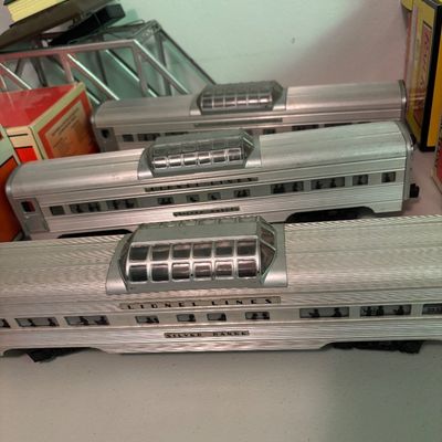 Three vintage Lionel Lines "Silver Range" O-gauge aluminum vista dome passenger cars, showing some light wear from age.