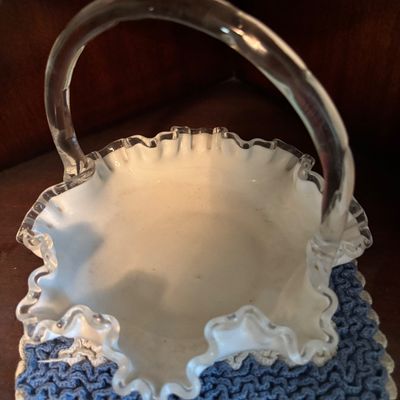Fenton-style white milk glass basket featuring a ruffled crest with clear glass trim and an attached clear glass handle.