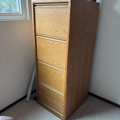Four-drawer oak filing cabinet with integrated wooden pull handles, showing a clean, modern design.