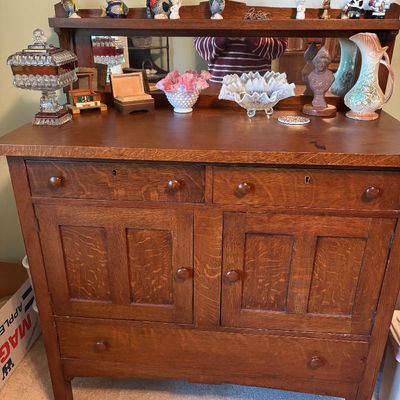 Antique quarter-sawn oak sideboard with a mirrored back gallery, featuring two upper drawers, two cabinet doors, and a wide lower drawer.