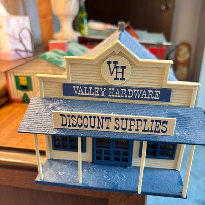 Vintage plastic toy storefront building for "Valley Hardware Discount Supplies" in cream and blue, showing some dust from storage.