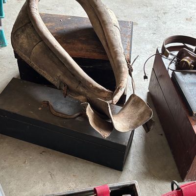 Antique leather horse collar showing significant wear and age, resting on a vintage wooden box.