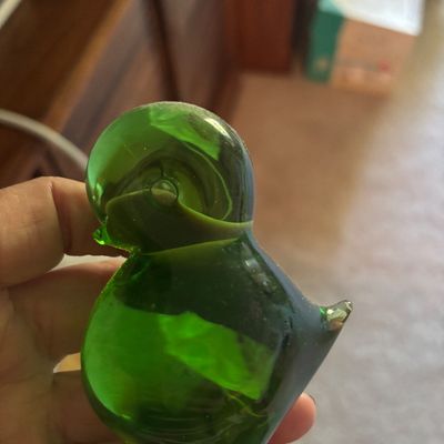 Vintage hand-blown green glass bird figurine, showing a smooth, rounded shape with a small pointed tail.