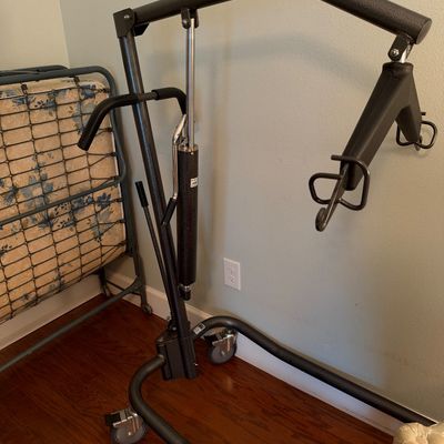 Sale Photo Thumbnail #112: Manual hydraulic patient lift with a black textured steel frame and caster wheels, 
