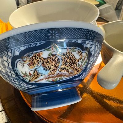 Vintage Japanese porcelain footed bowl featuring a hand-painted tiger illustration within a blue and white patterned border.