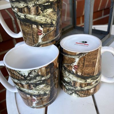 Set of three Mossy Oak ceramic coffee mugs featuring a realistic camouflage tree bark pattern.