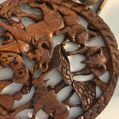 Hand-carved wooden openwork plaque depicting various African animals, including an elephant, giraffe, and lion, arranged in a circular...