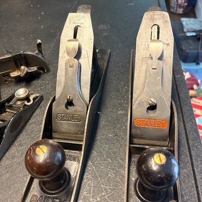 Two vintage Stanley Bailey hand planes with wooden knobs, showing some wear and patina from age and use.