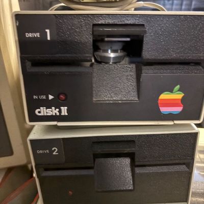 Vintage Apple Disk II floppy disk drives, labeled Drive 1 and Drive 2, featuring the classic rainbow Apple logo.