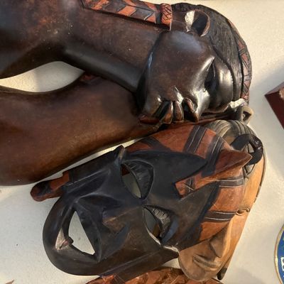 Collection of hand-carved African wooden masks and busts, featuring detailed facial features and rich dark wood finishes.