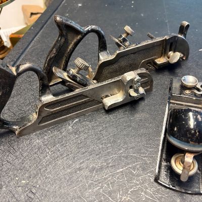 Vintage cast iron hand planes, including a specialty plow or combination plane and a small block plane, showing signs of age and use.