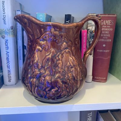 Sale Photo Thumbnail #126: Vintage brown glazed ceramic pitcher featuring raised relief hunt scenes around the body.
