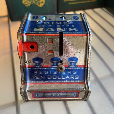 Sale Photo Thumbnail #97: Vintage tin litho Dime Register Bank with blue and red details, showing moderate surface wear and scratching.