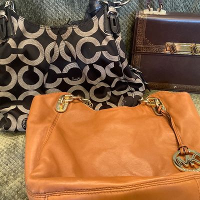 Sale Photo Thumbnail #185: Collection of women's handbags including a tan leather Michael Kors tote, a black and grey Coach jacquard signature shoulder bag, and a vintage dark brown structured purse.