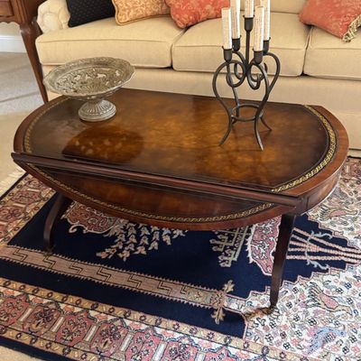 Sale Photo Thumbnail #29: Traditional oval mahogany drop-leaf coffee table with gold-tooled leather inlay.