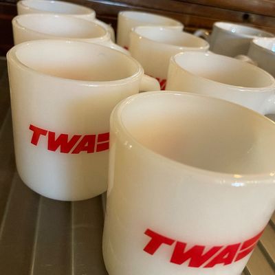 Sale Photo Thumbnail #110: Collection of vintage white milk glass coffee mugs featuring the red TWA logo.