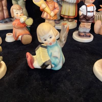 Sale Photo Thumbnail #95: Collection of vintage Goebel Hummel porcelain figurines featuring children with musical instruments and traditional attire.