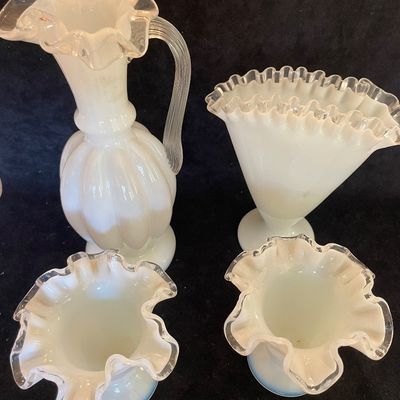 Sale Photo Thumbnail #102: Four-piece collection of Fenton-style opalescent milk glass glassware, featuring clear crest ruffled edges and including a pitcher, fan vase, and a pair of small vases.