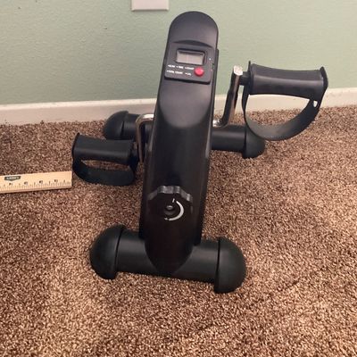 Sale Photo Thumbnail #61: Compact under-desk pedal exerciser in black plastic with adjustable resistance knob and digital display.