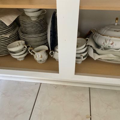 Sale Photo Thumbnail #67: Vintage fine china dinnerware set featuring delicate floral patterns and gold trim, including plates, teacups, a creamer, and a covered tureen, stored in a cabinet.