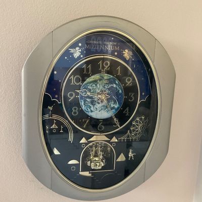 Sale Photo Thumbnail #11: Seiko "Celebrate the New Millennium" musical wall clock, featuring a silver-tone oval frame, an Earth-themed dial, and a rotating pendulum, circa 2000.