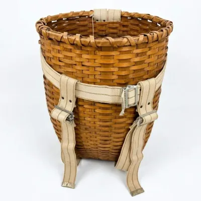 Sale Photo Thumbnail #11: Vintage Adirondack pack basket woven from splint wood, featuring adjustable canvas harness straps with metal buckles.