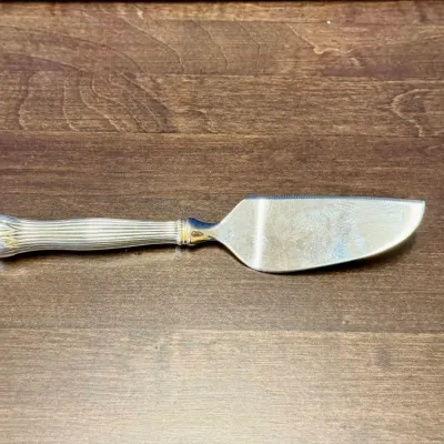 Sale Photo Thumbnail #20: Vintage silver-plated cake or pie server featuring a ribbed, column-style handle and a serrated edge.