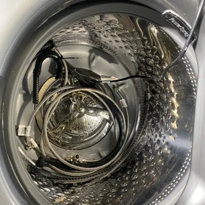Sale Photo Thumbnail #20: Interior view of a Maytag top-load washing machine drum, showing the stainless steel tub, agitator, and included connection hoses.