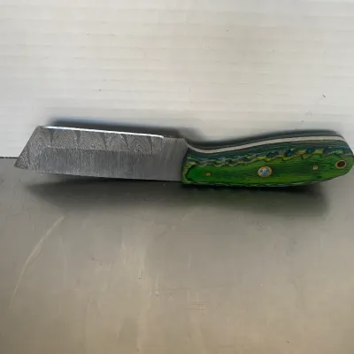 Sale Photo Thumbnail #46: Custom Damascus steel cleaver-style knife featuring a vibrant green and blue laminated wood handle with a decorative mosaic pin.