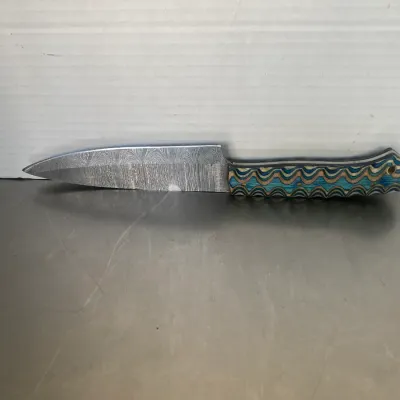 Sale Photo Thumbnail #39: Custom fixed-blade knife featuring a Damascus steel blade and a textured, multi-colored blue and tan handle.