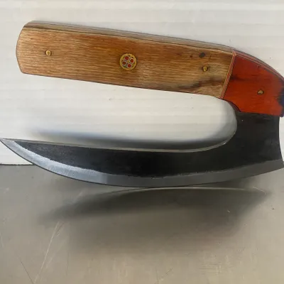 Sale Photo Thumbnail #67: Handcrafted ulu knife featuring a curved steel blade and a wooden handle with a decorative mosaic pin inlay.