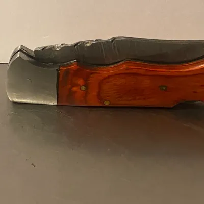 Sale Photo Thumbnail #72: Vintage folding pocket knife featuring a polished wood handle with brass pins and a stainless steel bolster.
